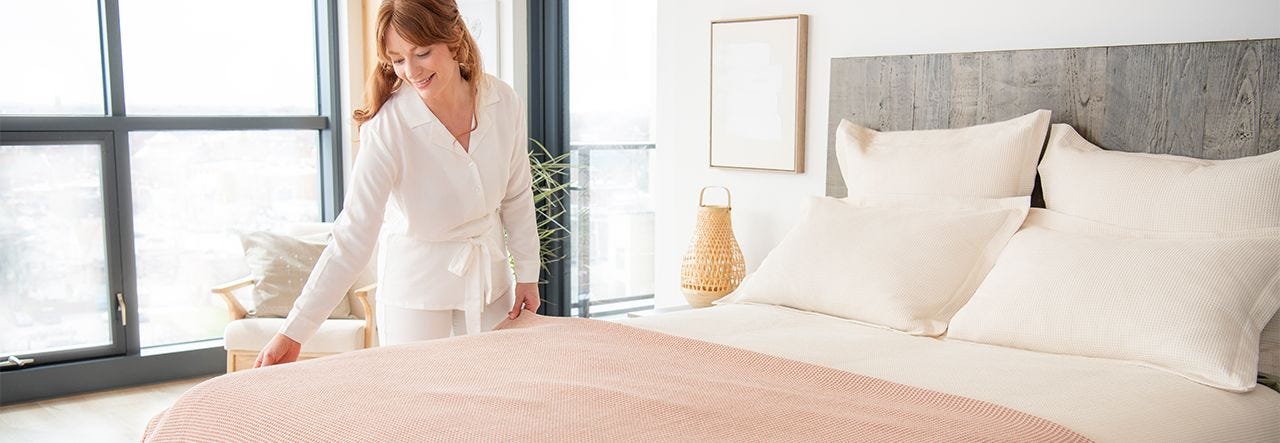 woman making her bed with waffle weave blanket