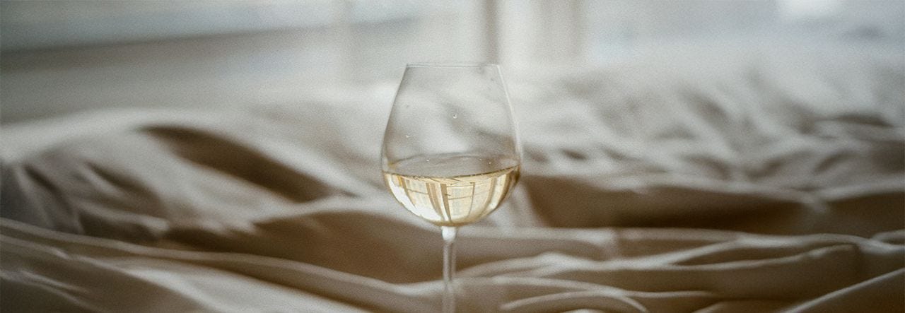 glass of white wine on a bed