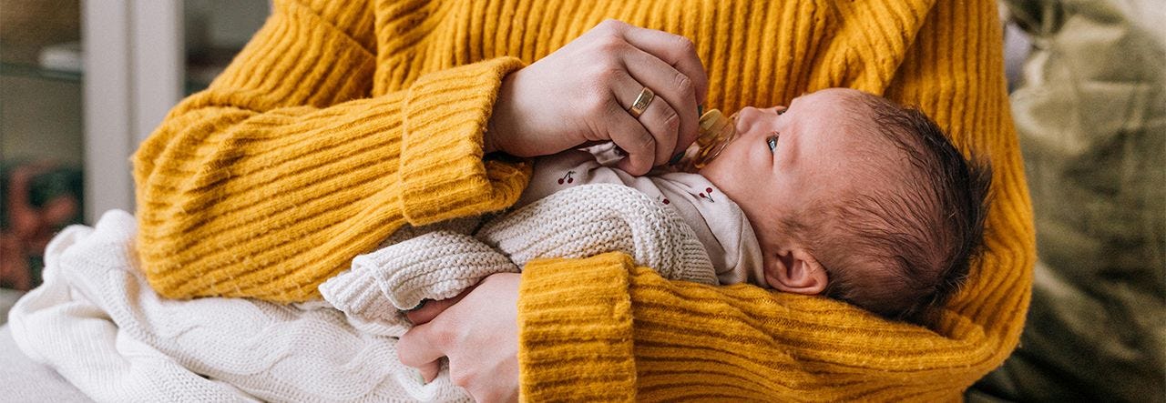baby being held by parent in yellow sweater