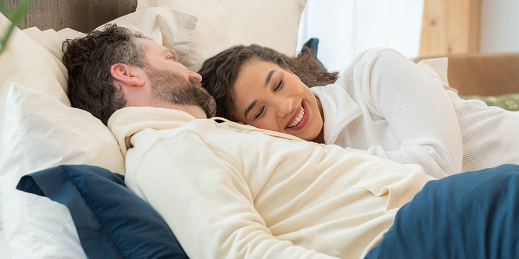 couple laying together in bed with sateen sheets