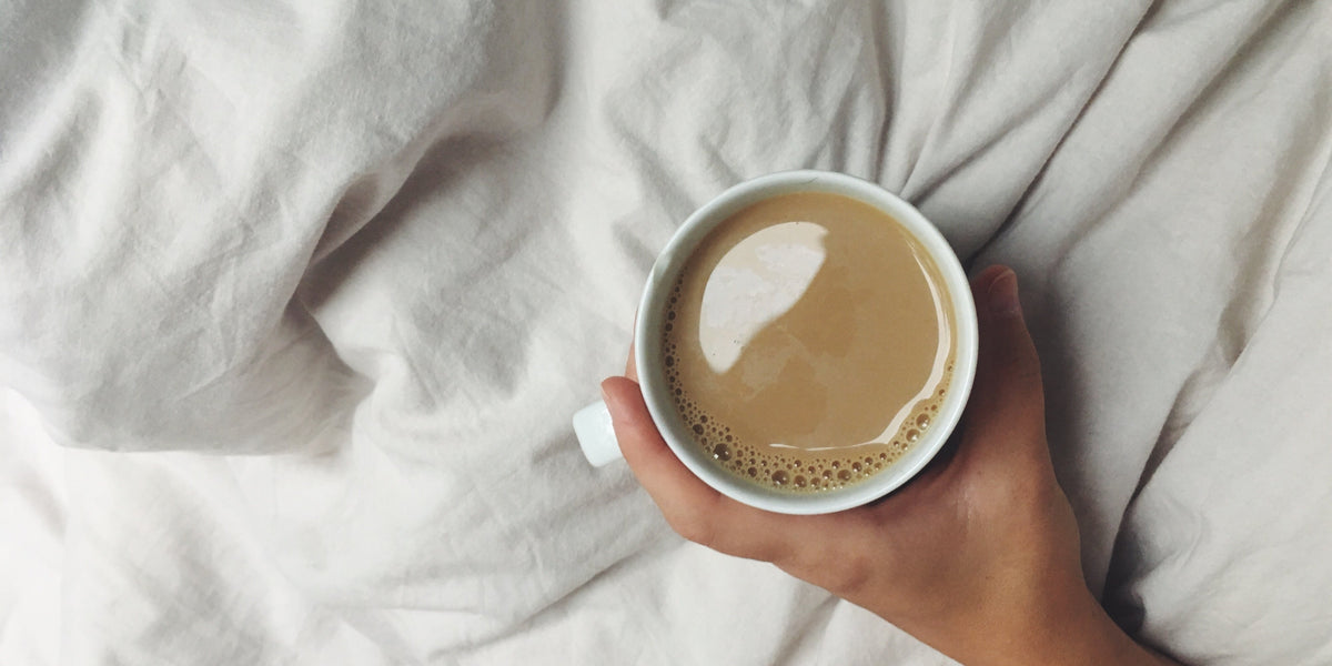 Cup of coffee on a bed with white bedding