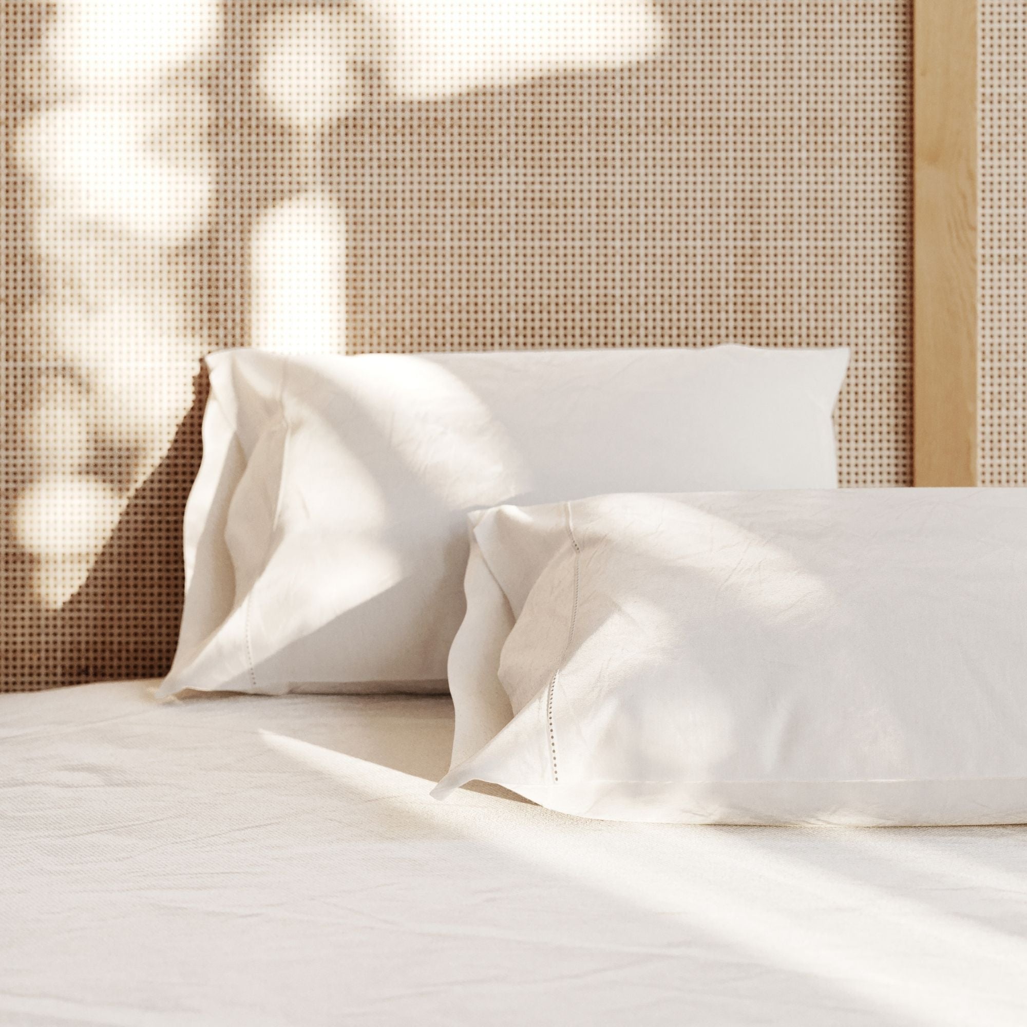 White pillows on a bed with a woven headboard