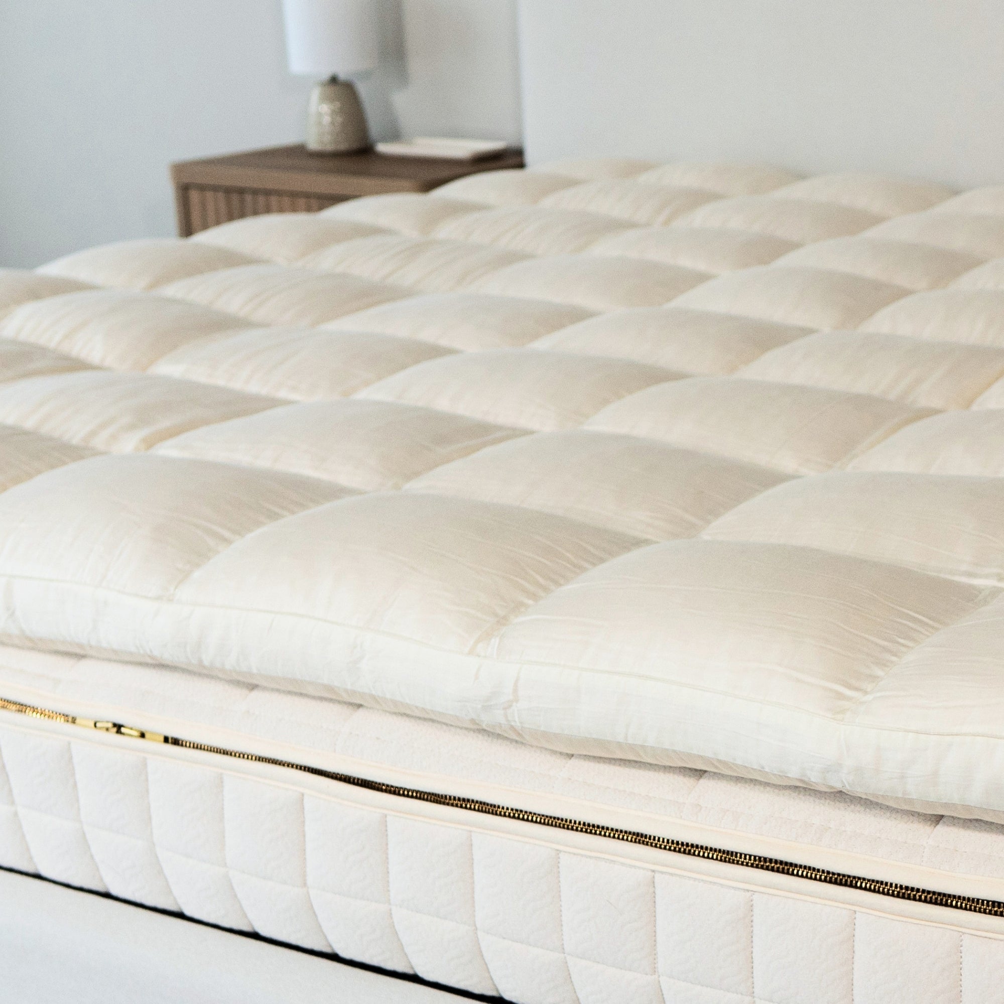 White quilted mattress topper on a bed in a bedroom setting.