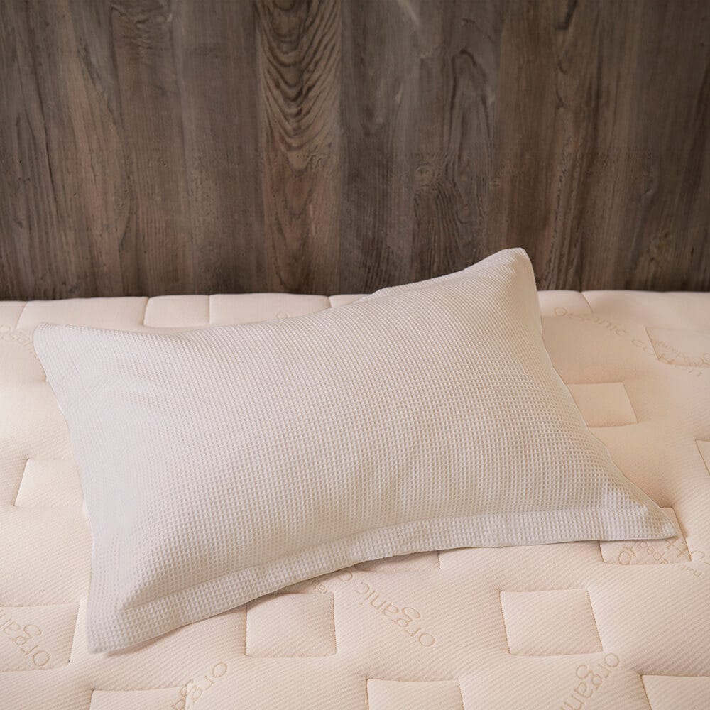 Beige pillow on a textured mattress with a wooden headboard. #color_cream