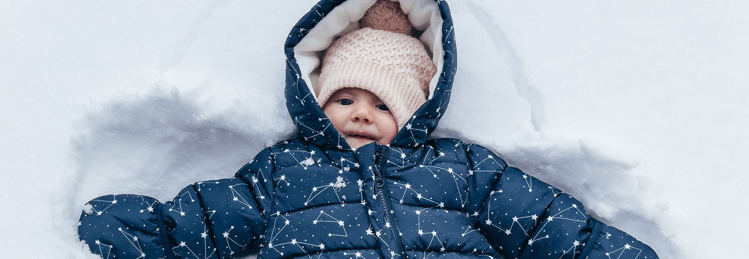 Parent tucking their newborn into the carseat on a cold day