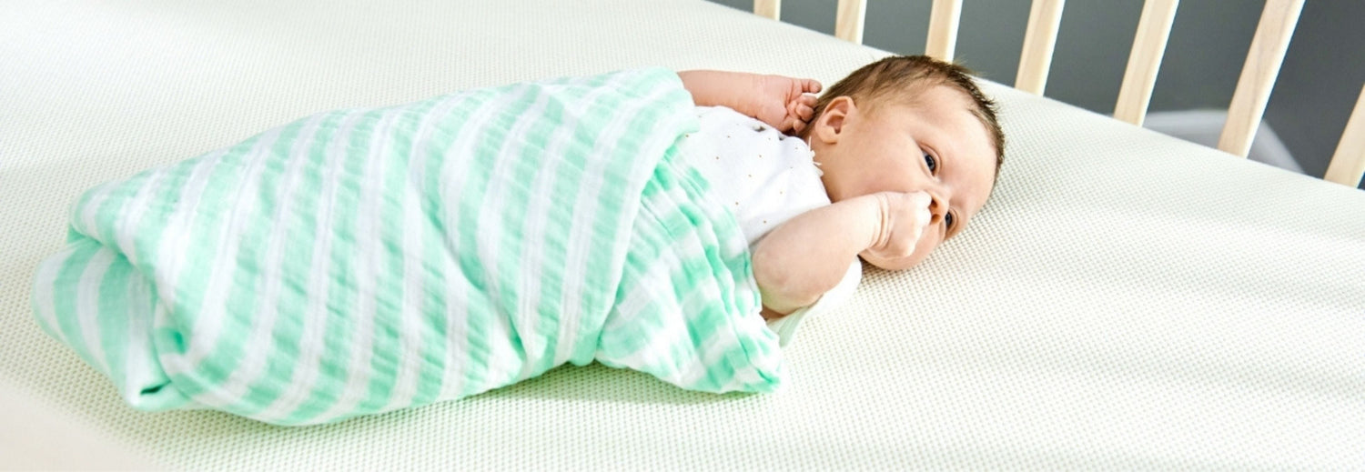 swaddled baby on a breathable crib mattress