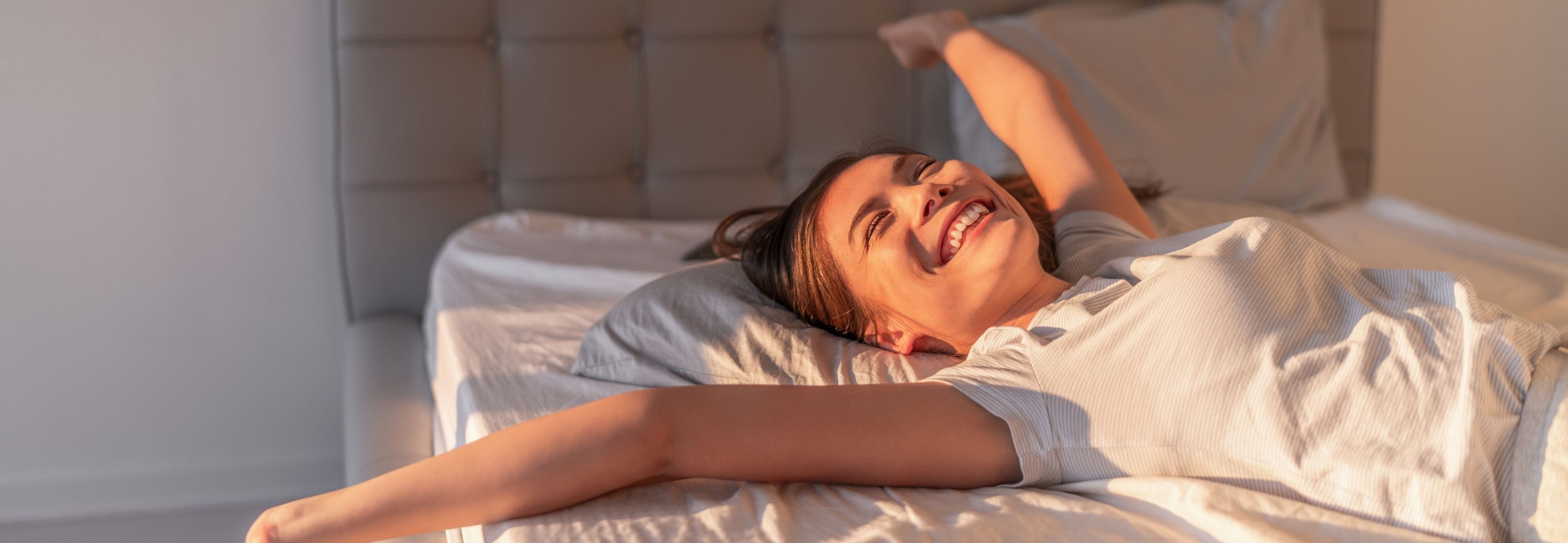 woman waking up in bed in the morning and stretching