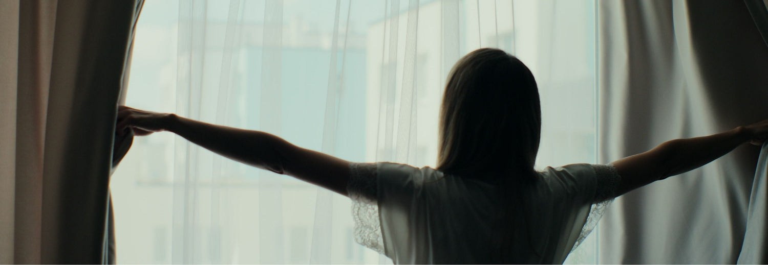 woman opening the blinds in the morning