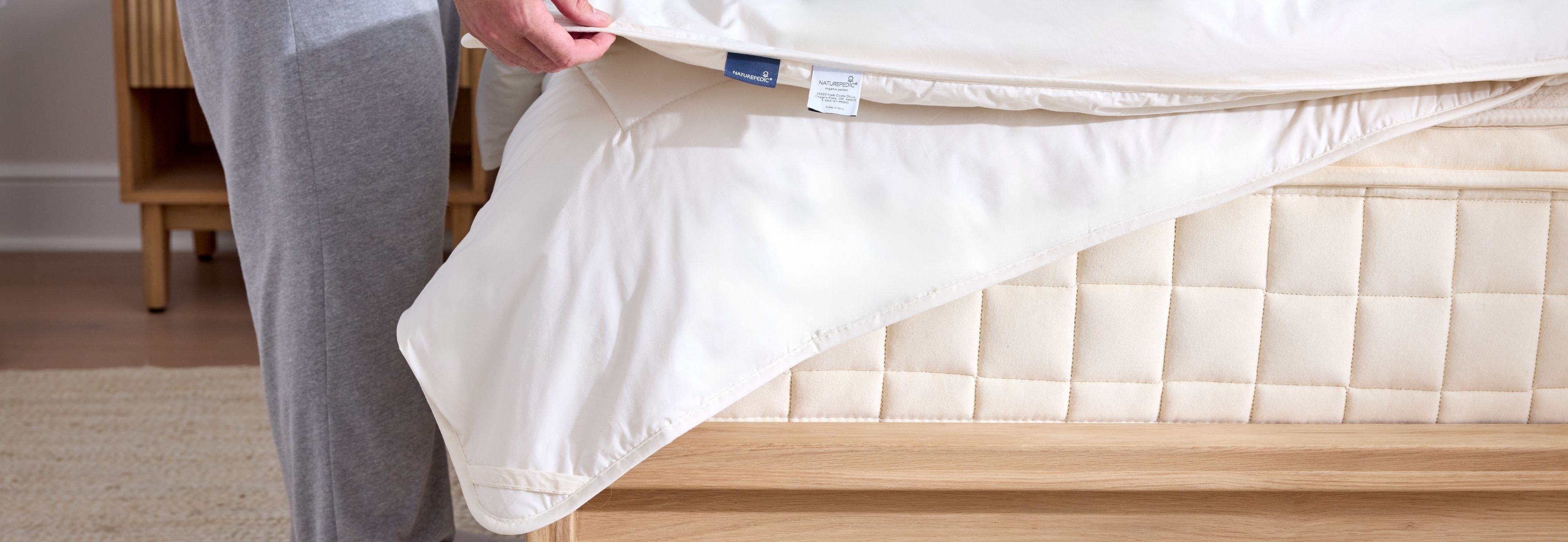 person putting a high-GSM comforter on a bed