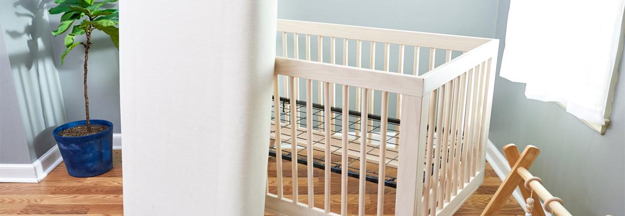 Crib mattress leaning against an empty crib in a nursery