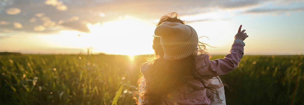 parent holding child at sunset