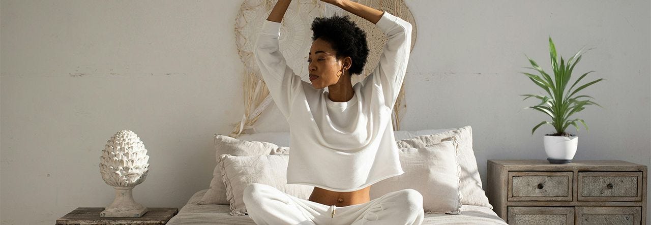 Refreshed woman sitting up in bed and stretching her arms over her head