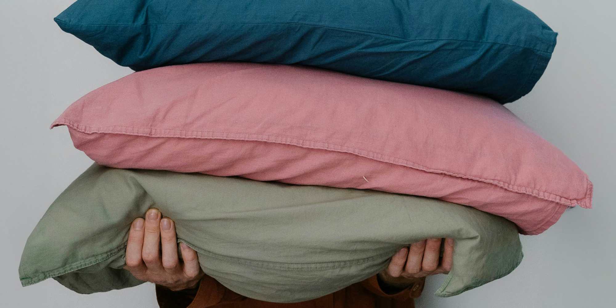 person holding a colorful stack of old pillows