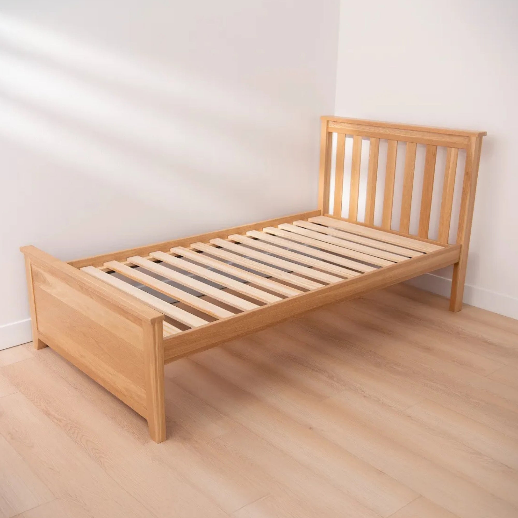 Wooden bed frame on a wooden floor with a white wall background #size_twin platform  #color_natural