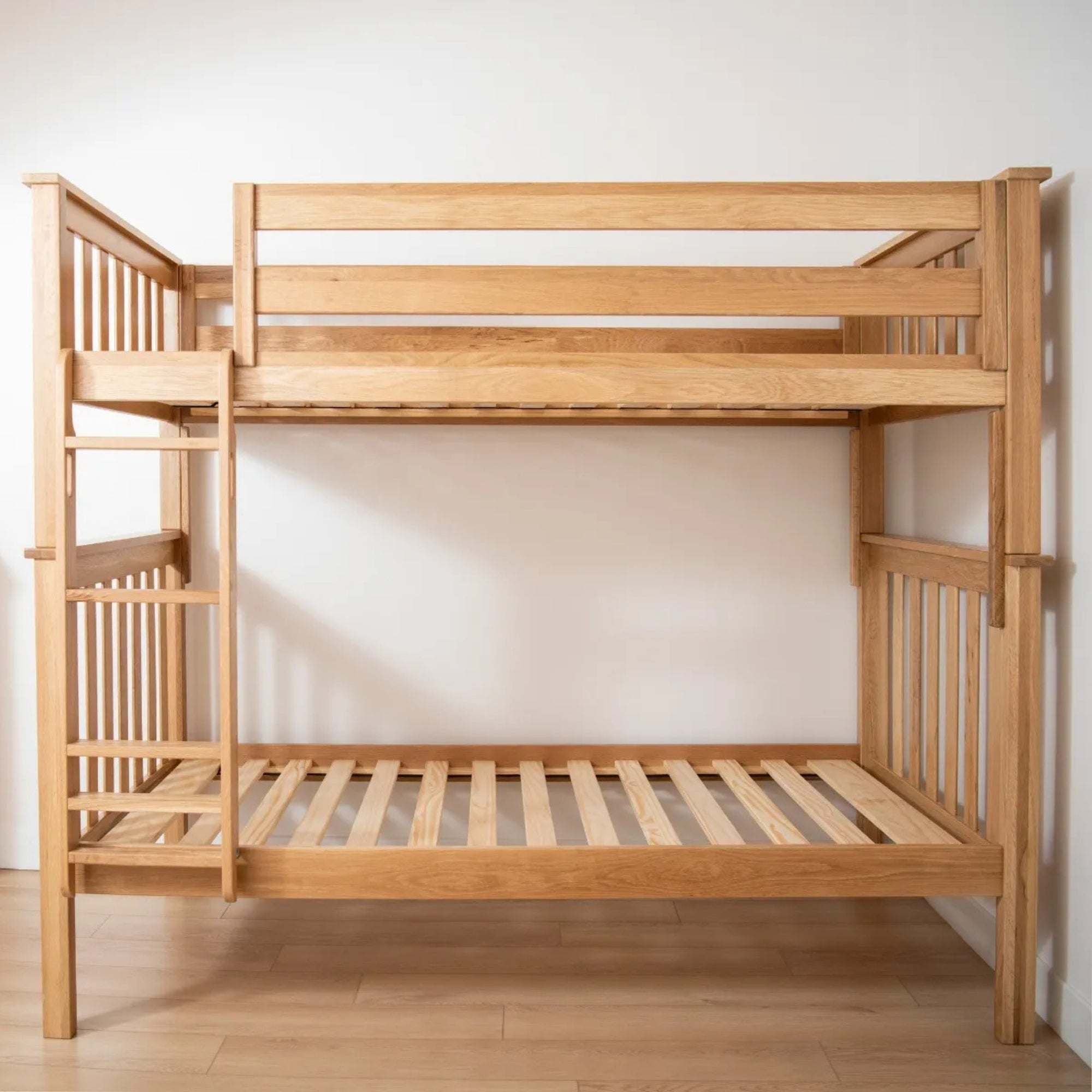 A light natural oak bunk bed with a built-in ladder against a plain off-white wall #size_Twin/Twin bunk #color_natural 