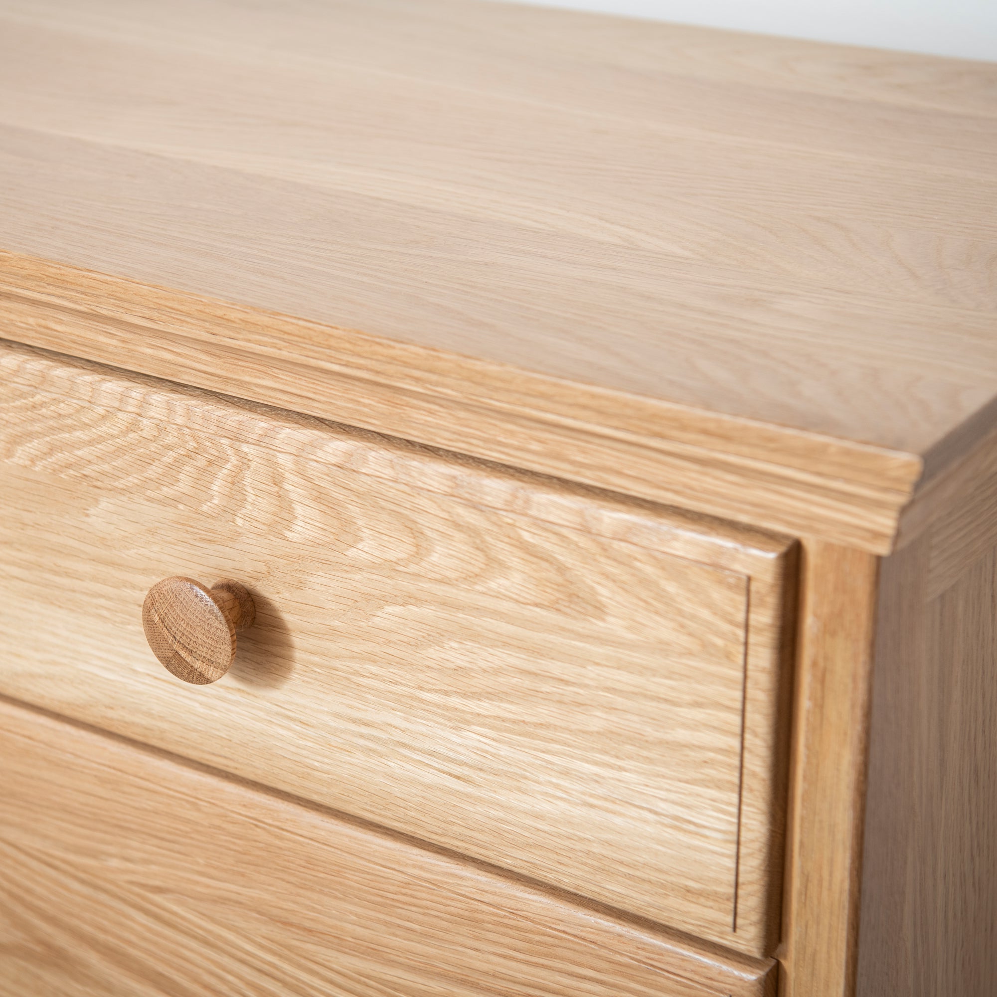 Close-up of a wooden drawer with a knob on a light wood background #color_natural
