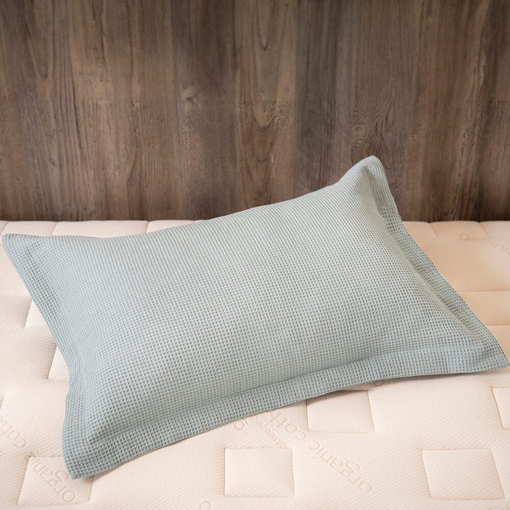 Light blue textured pillow on a beige bed against a wooden headboard. #color_harbor island